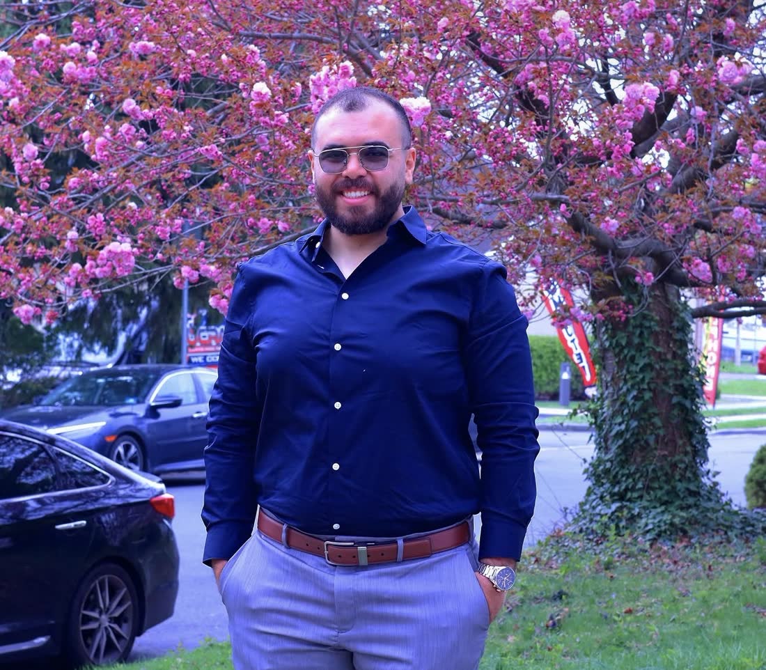 Ahmed Alassar, sales consultant, smiling in a navy shirt