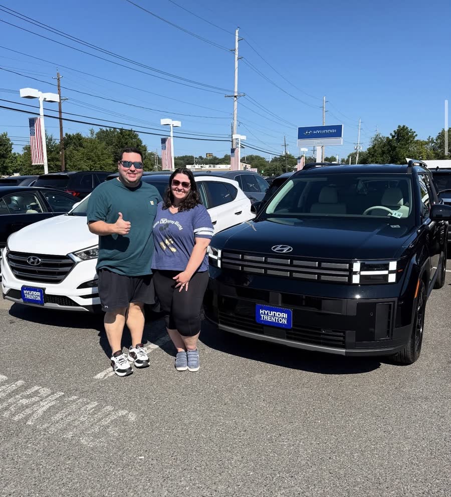A couple giving a thumbs up next to their new black Santa Fe