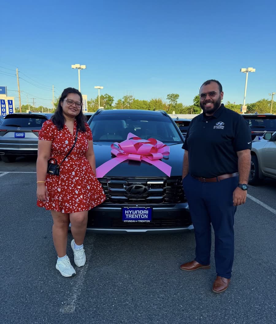 Ahmed with a customer beside her new Tucson Hybrid with a pink bow on the hood