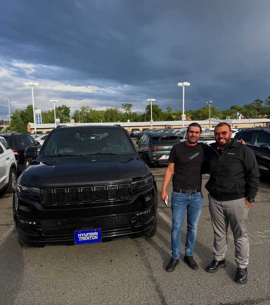 Ahmed with a customer next to a black Wagoneer